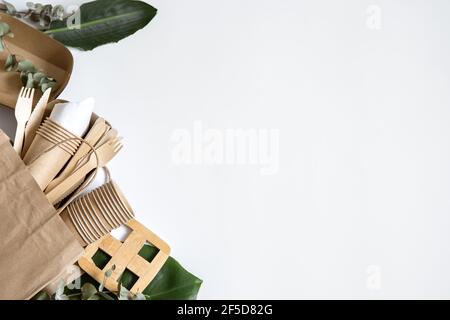 Paper bag with disposable eco friendly tableware, plates, glasses top view. Stock Photo