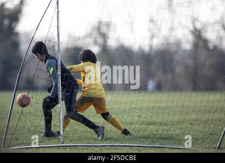 Oadby, Leiecstershire. England. March 2021. Children play football in a park with a mobile pop-up goal. Stock Photo