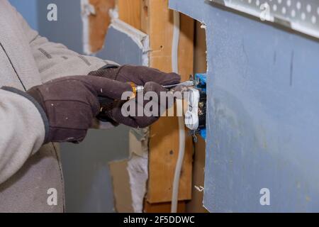 Preparing to remove an electrical outlet of the screws for electrical wires receptacle plug panel Stock Photo