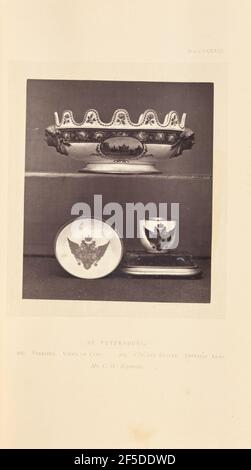 Verrière. A verriere on a shelf above a cup and saucer. The verriere has a scalloped edge and handles in the shape of faces in relief. It is painted with a cityscape in an oval medallion, along with flowers and a floral border. The cup and saucer are both decorated with painted imperial arms of Paul I of Russia.. (Recto, mount) upper right, printed in black ink: 'PLATE CXXXIII.' Lower center, printed in black ink: 'ST. PETERSBURG. / 266. VERRI»RE. VIEWS OF CITY. 265. CUP AND SAUCER. IMPERIAL ARMS. / Mr. C. W. Reynolds. italicized' Stock Photo