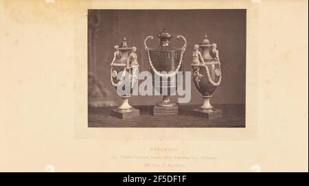 Three vases. Three vases side by side. All three vases are decorated with festoons in relief. The vases on the left and right are a pair and each feature two handles in the form of a woman holding on to the garland. The center vase has two curved, upward pointing handles.. (Recto, mount) lower center, printed in black ink: "WEDGWOOD. / 313. THREE GRANITE VASES, GILT FESTOONS AND HANDLES. / Mr. John J. Bagshawe. italicized" Stock Photo