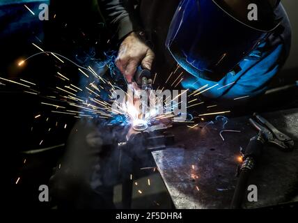 welder in mask welds metal details Stock Photo