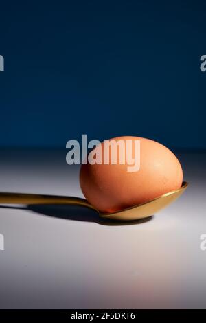 Red egg with a golden spoon on a gray background. High quality photo Stock Photo