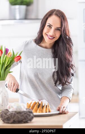 Young woman cutting sweet easter cake during holidays. Stock Photo