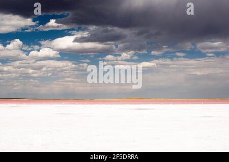 white salt lake with pink shore and clouds in the sky Stock Photo