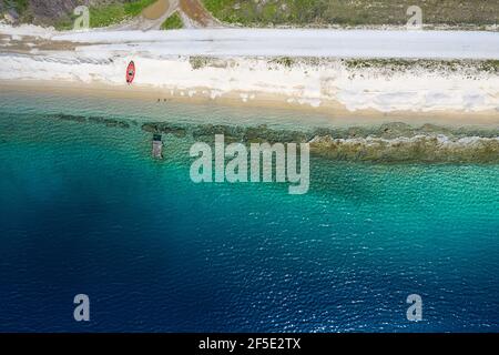 Aerial panorama of Mediterranean sea coast with white sand beach road and blue water. Top view of sail boat and pier with copy space tropical summer b Stock Photo