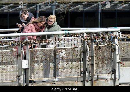 Bristol, UK. 26th Mar, 2021. People are out in the spring sunshine in Bristol despite Covid lockdown and recent protests. Two ladies checking the lovelocks on Pero's bridge in the sun. Credit: JMF News/Alamy Live News Stock Photo