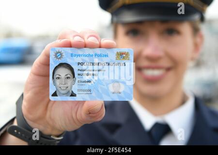 26 March 2021, Bavaria, Roding: A police officer shows a sample of the new Bavarian police ID card at a press event. After 35 years, the old green service cards are being replaced by a new, particularly forgery-proof card in credit card format. Photo: Tobias Hase/dpa Stock Photo