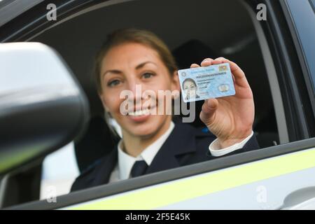 26 March 2021, Bavaria, Roding: A police officer shows a sample of the new Bavarian police ID card at a press event. After 35 years, the old green service cards are being replaced by a new, particularly forgery-proof card in credit card format. Photo: Tobias Hase/dpa Stock Photo