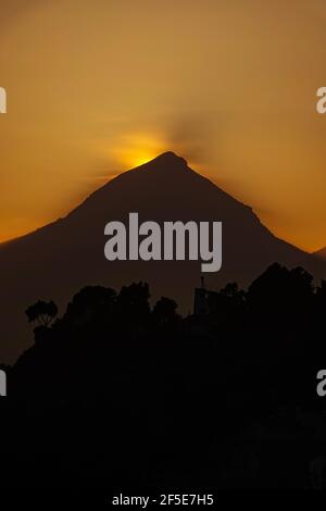 The sun setting behind the triangular peak of the Puig Campana, near Benidorm at the Costa Blanca, Spain Stock Photo