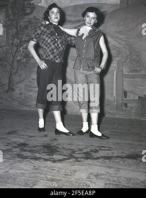 1956, historical, standing on a stage, two young ladies in the costumes of their characters from the play, Jack & the Beanstalk, England, UK. An ancient folk story, it was first published as an English fairy tale, 'The Story of Jack Spriggins and the Enchanted Bean' in 1734 and then in 1807 in 'The History of Jack and the Bean-Stalk' by Benjamin Tabert.  Fairy tales are ancient folklore, featuriing mythical creatures; elves, fairies, talking animals, witches and giants in magical stories that are far-fetched and not true and indeed could not possiblly be true. Stock Photo