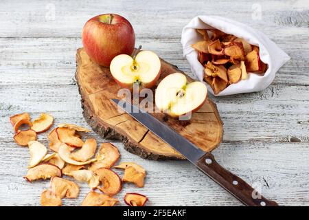 A pile of dried slices of apples and fresh ripe apples on wooden background. Dried fruit chips. Healthy vegan food Stock Photo