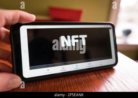 Andover, MA, US-March 24, 2021: Person holding phone with NFT logo on it. Stock Photo