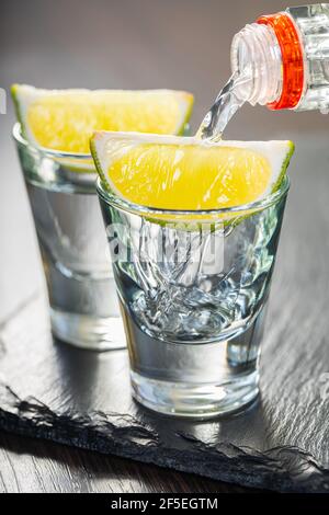 strong alcohol pouring into shot glasses on wooden background Stock Photo