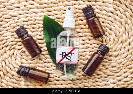 Homemade essential oil based mosquito repellent. Flat lay view of spray bottle surrounded by brown essential oil bottles on bamboo mat background. Stock Photo