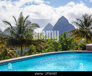 Soufriere, St Lucia. View to the Pitons across empty swimming pool, coconut palms on hillside. Stock Photo