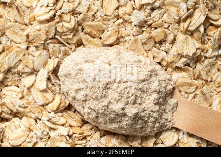 Spoonful of oat flour on top of uncooked porridge oats. Top view. Background. Stock Photo
