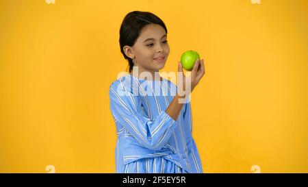 happy child holding green apple isolated on yellow Stock Photo