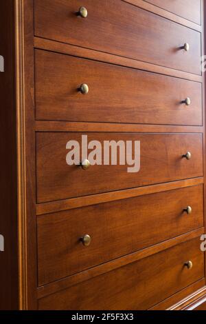 Maple wood dresser with brass metal knobs on drawers in guest bedroom inside an old 1807 cottage style house Stock Photo