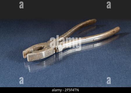 Iron pliers lie on a table with a reflection. Locksmith tools on a black background Stock Photo