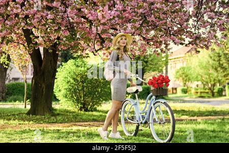 Active day. cherry tree pink blossom. perfect smell. perfume spa and allergic. travel. retro woman sell tulip flower bouquet. girl under sakura with Stock Photo