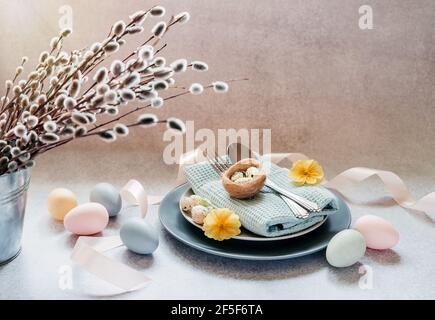 Easter table setting ideas, minimal decoration - Easter eggs, willow catkin branches, bird's nest on light gray background with copy space Stock Photo