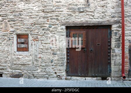 White brick wall with old wooden front door, window and red rainwater downpipe. Architectural details Stock Photo