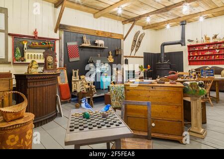 Native-made and antique wooden furniture pieces and objects on display inside an old wood plank barn Stock Photo