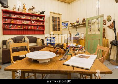Antique wooden dining table, bird, duck decoys and animal wood carvings on display inside an old wood plank barn Stock Photo