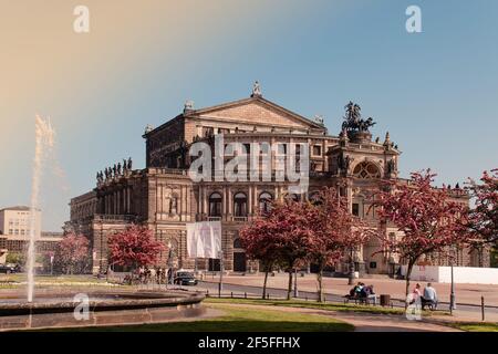 17 May 2019 Dresden, Germany - Dresden Semper Opera theatre (Semperoper), front view in spring. Blooming branches on foreground. Stock Photo
