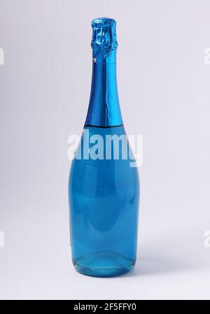 Shimmer edible glitter sparkling blue champagne in bottle on white background. Vertical format Stock Photo