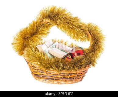 Wicker basket full of euro bills with christmas golden tinsel and bright Christmas balls. Isolated on a white background. Stock Photo