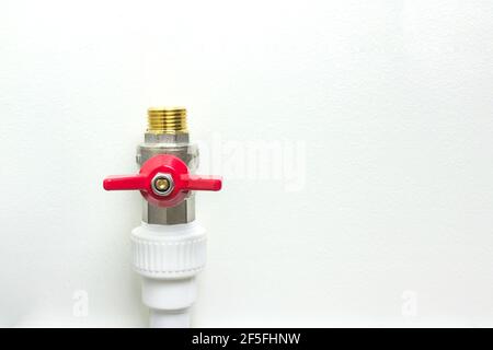 White polypropylene pipe and red faucet. Fittings for water pipes - an example of a connecting unit when creating a water supply system of PVC pipes. Stock Photo