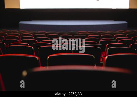 Cinema interior. Chairs in a large empty cinema hall against a white projection screen Stock Photo