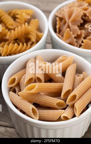 Narrow focus closeup of assorted whole wheat pasta on bowls. Stock Photo
