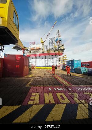 offshore supply vessel slowly approaching to oil rig during 500 meter zone to oil rig for cargo supply Stock Photo