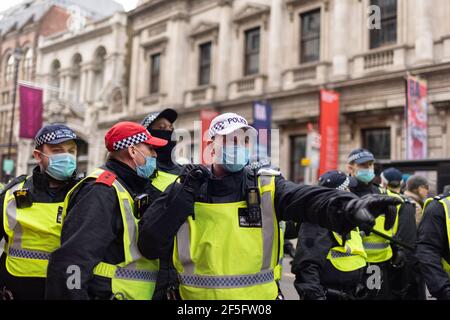 Anti-lockdown and anti Covid-19 vaccination protest, London, 20 March 2021. A police officer with baton raised. Stock Photo