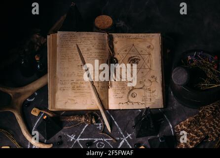 Wizard Spell Runes Witch book of spells with black candles on altar table. Occult ...