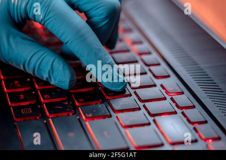 Hands in medical gloves type on a laptop keyboard in close-up. The concept of protection while working in quarantine Stock Photo