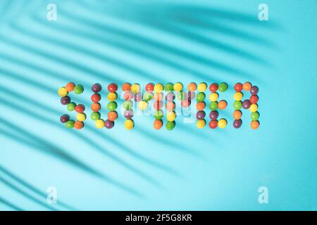 Summer word made from colored balls on a blue background with palm leaf shadow. Tropical summer flat lay concept. Stock Photo