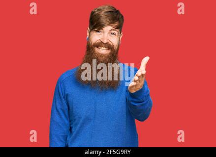 Young irish redhead man wearing casual clothes smiling friendly offering handshake as greeting and welcoming. successful business. Stock Photo