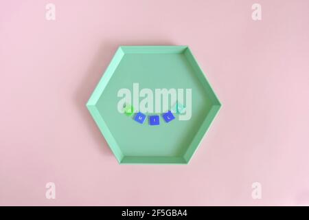 SMILE - word made from colored letters on green hexagon plate on pink background. Top view. Copy space. Selective focus. Stock Photo