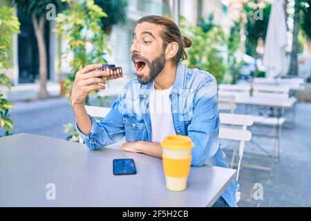 Young middle eastern man having breakfast at the coffee shop terrace. Stock Photo