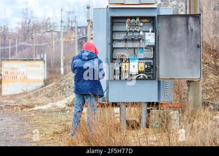 Transformer substation stands in the middle of the garden against a blue cloudy sky. Stock Photo