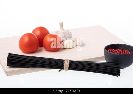 Uncooked black spaghetti pasta tied with a rope on a wooden cutting board Stock Photo