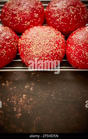 Fresh baked red homemade burger buns with sesame top view. Placed on metal grill.