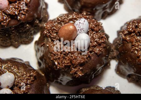 A selection of Easter Chocolate nest Cakes topped with three little chocolate mini eggs on a white plate Stock Photo