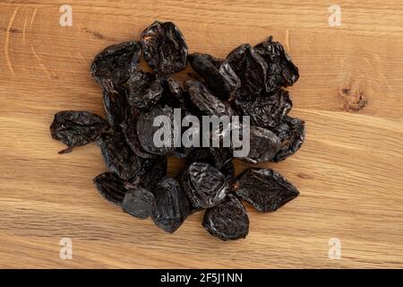Pile of prunes, dry plums isolated on wood background. Heap of dried fruits. Stock Photo