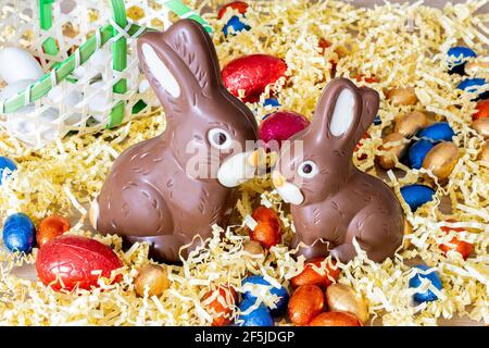 Easter. Two chocolate bunnies on straw, with easter eggs Stock Photo