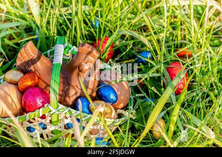 Easter. Chocolate hen and Easter eggs, in a basket on the grass Stock Photo